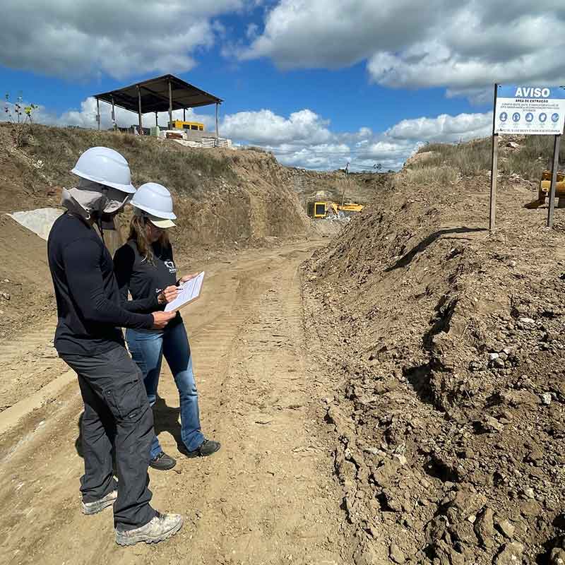 Engenheiro de minas e Geóloga numa pedreira analisando uma planilha de informações.